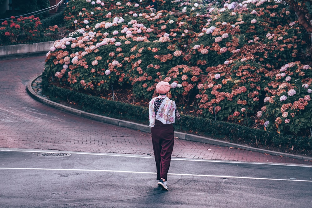 person walking on road near flower garden during daytime