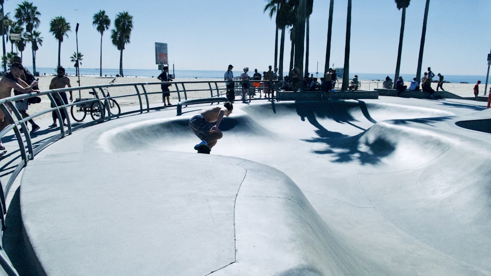 topless man skateboarding on ramp surrounded with people watching under blue and white sky during daytime