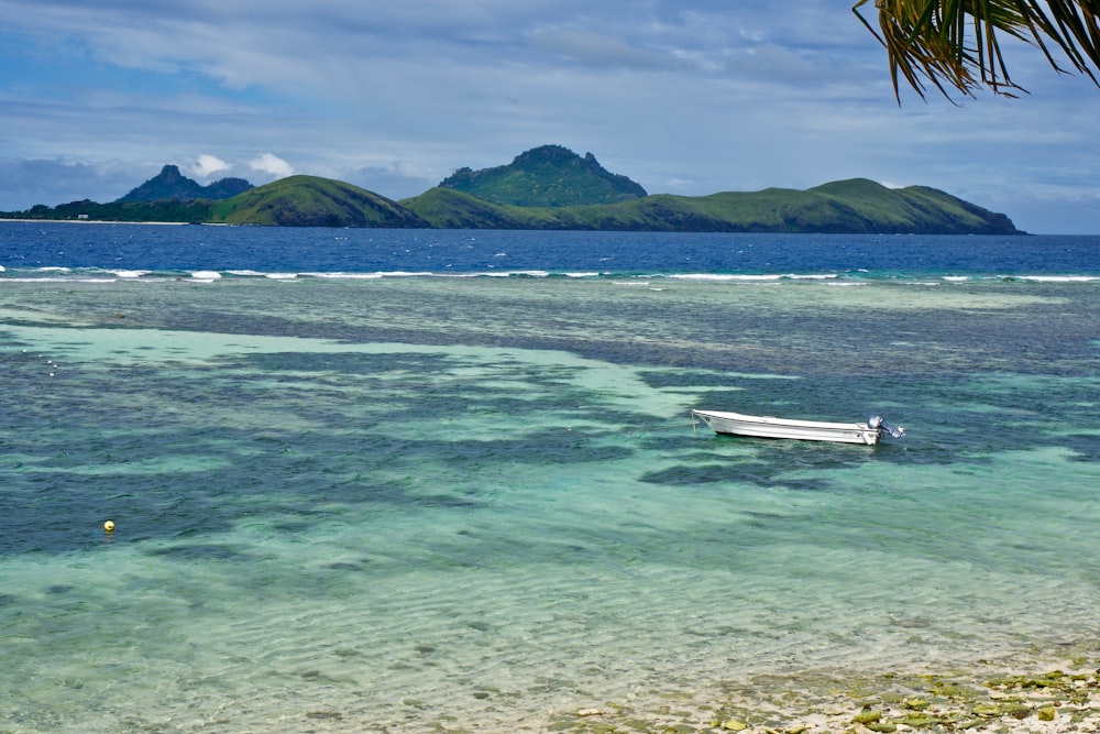 white wooden boat on sea near mountain