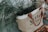 A jute tote bag with brown handles labeled 'Goods and Provisions', containing green fir branches. The bag is placed on a surface scattered with dry, brown leaves.