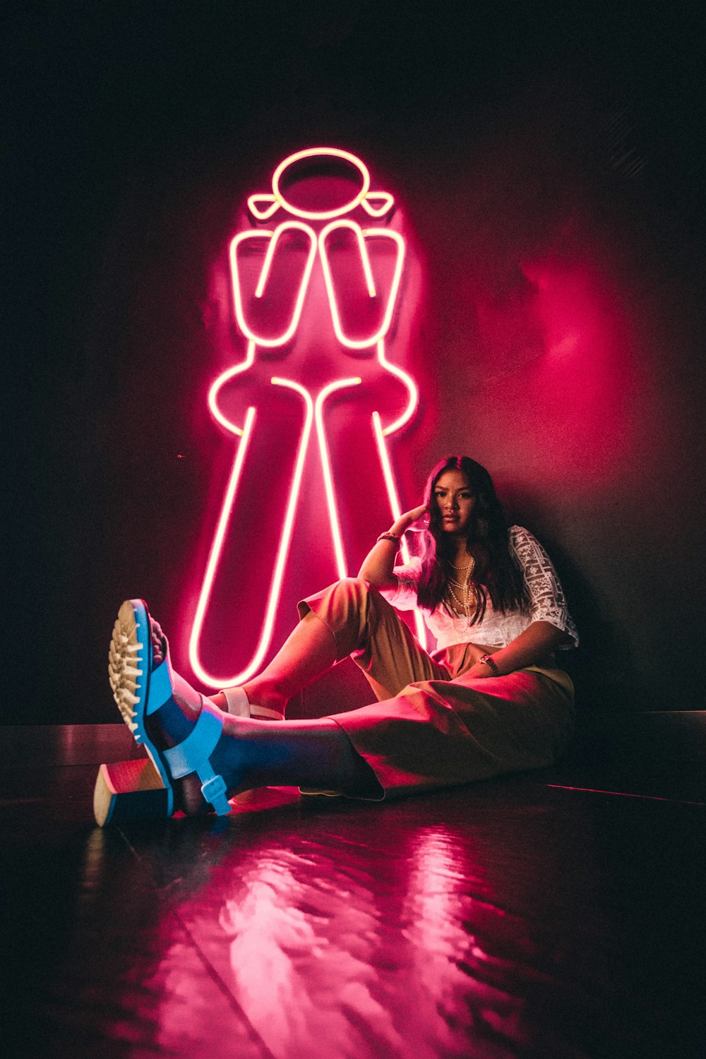 woman sitting and leaning against the wall near pink LED light