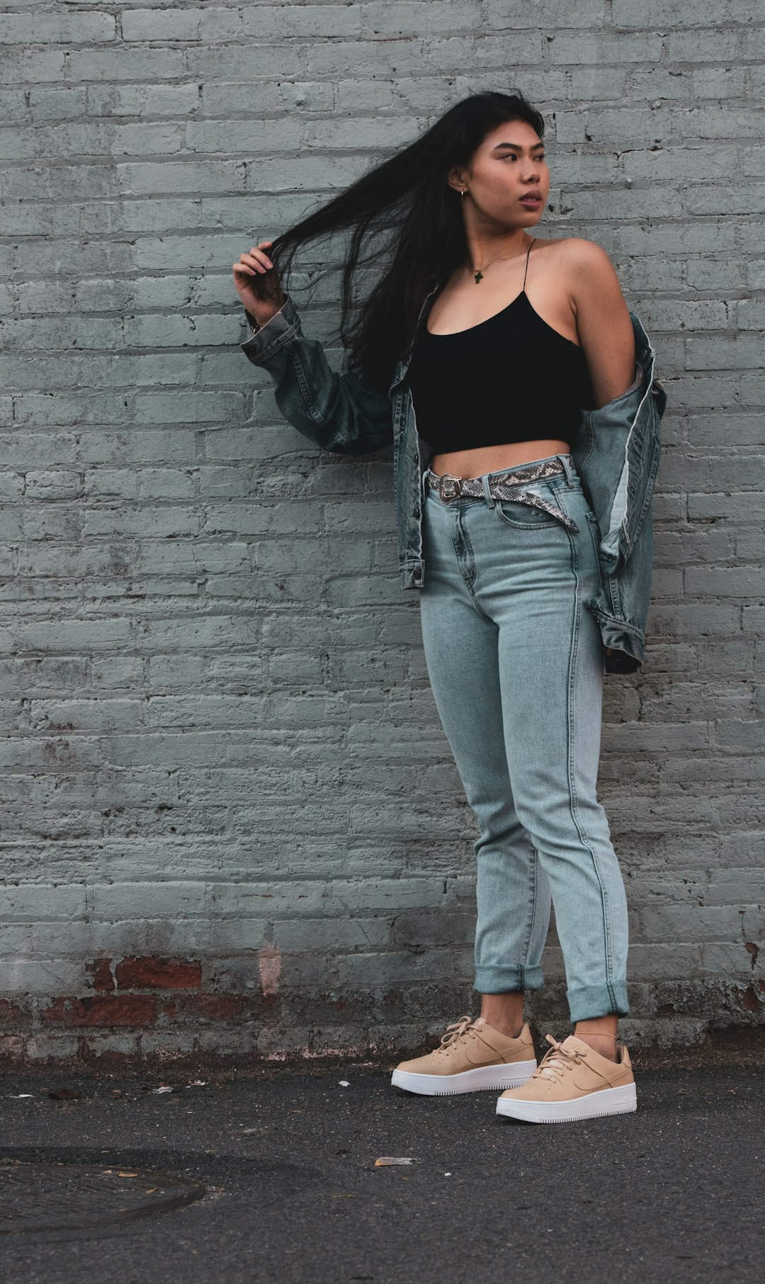 woman wearing black spaghetti strap top and blue denim jacket standing