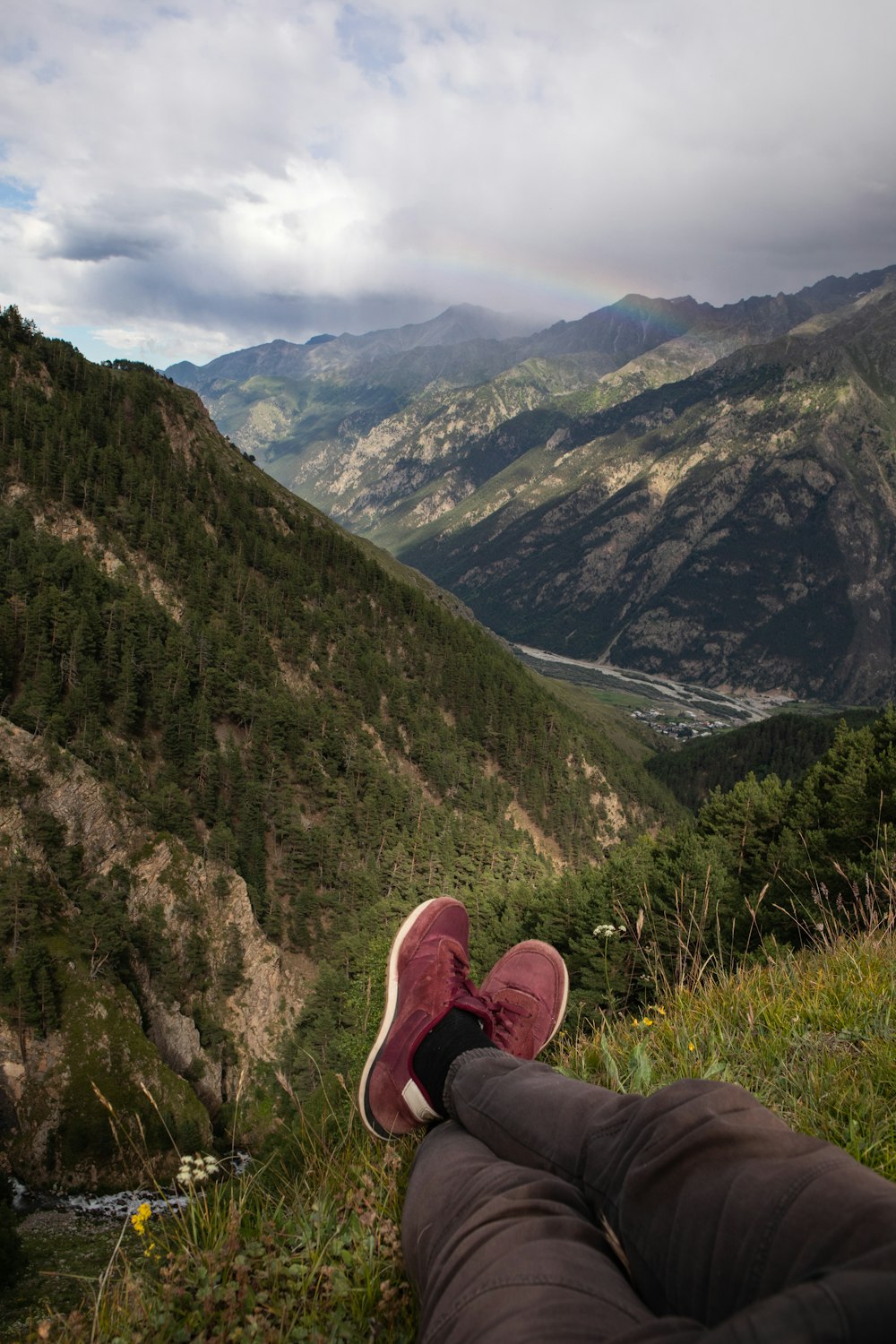 person sitting on top of mountain overviewing river and mountain