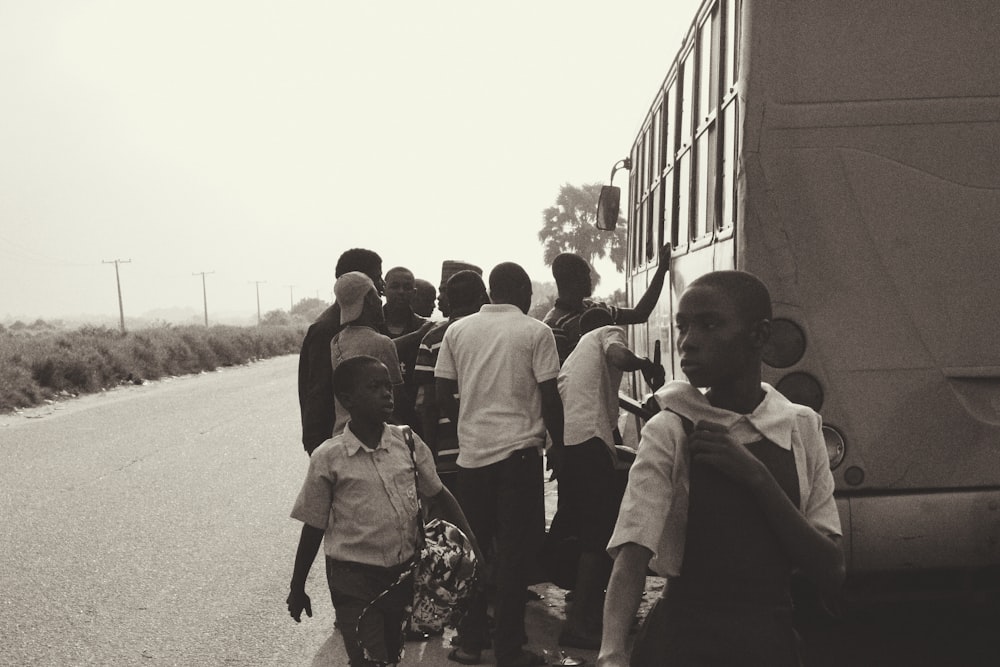 grayscale photography of people standing near bus