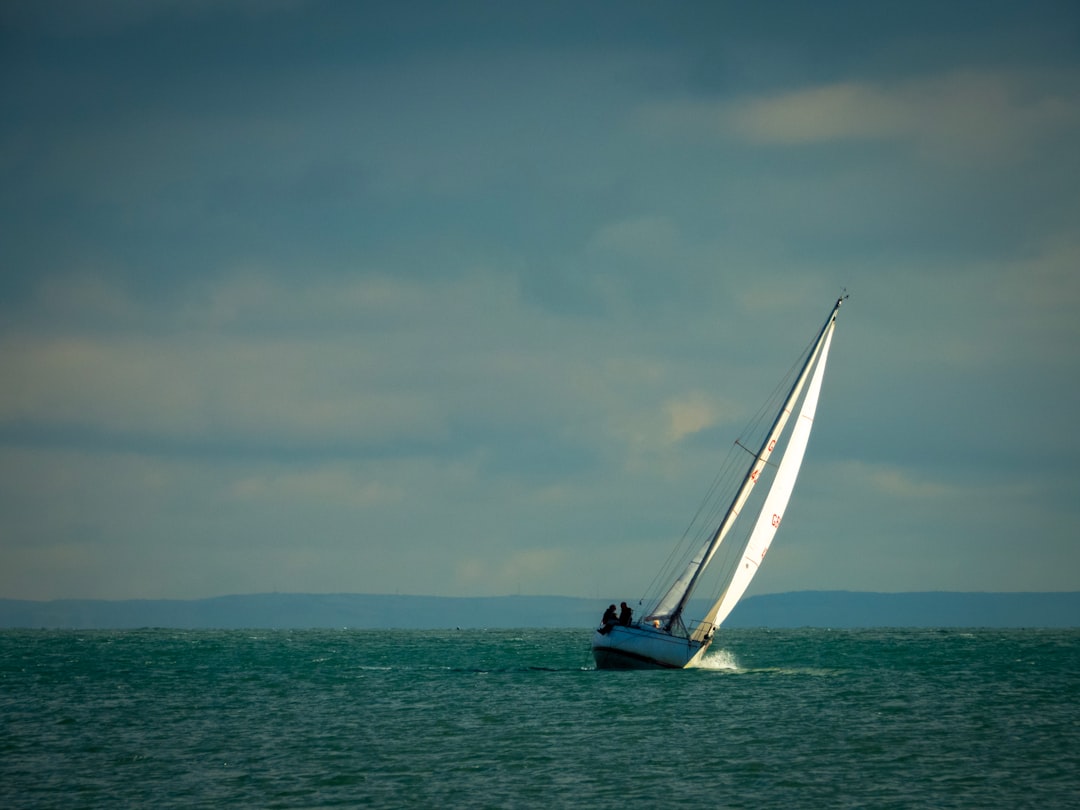 people in white and blue boat on body of water under blue and white sky during daytime