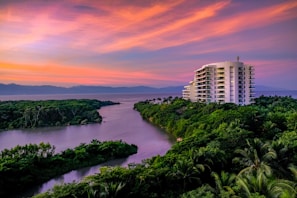 white building surrounded by trees and body of water