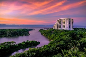 white building surrounded by trees and body of water