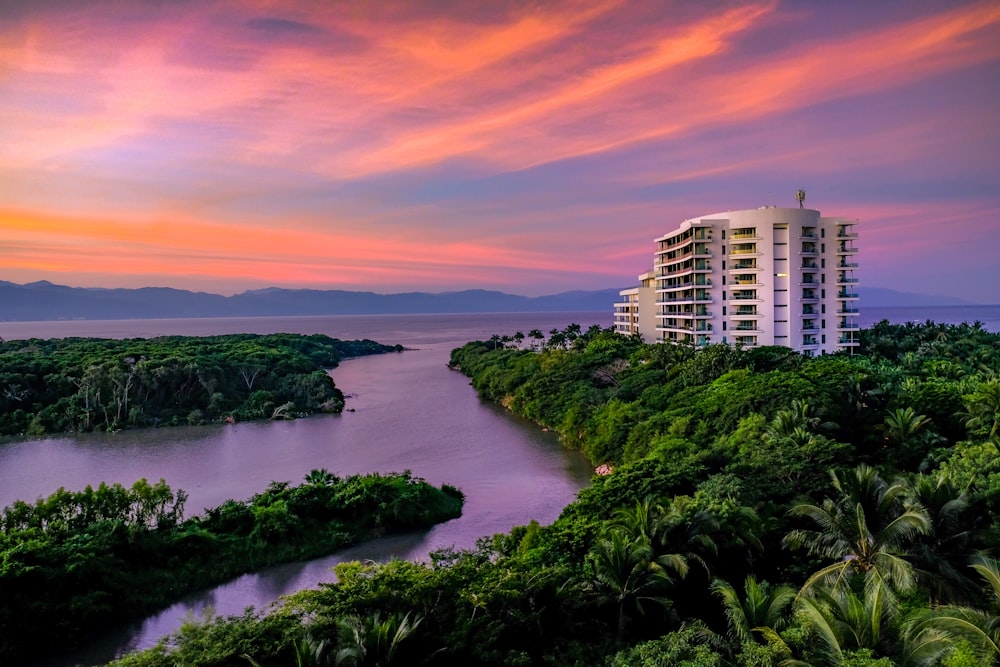 white building surrounded by trees and body of water