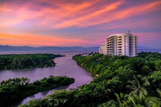 white building surrounded by trees and body of water in Nuevo Vallarta Mexico