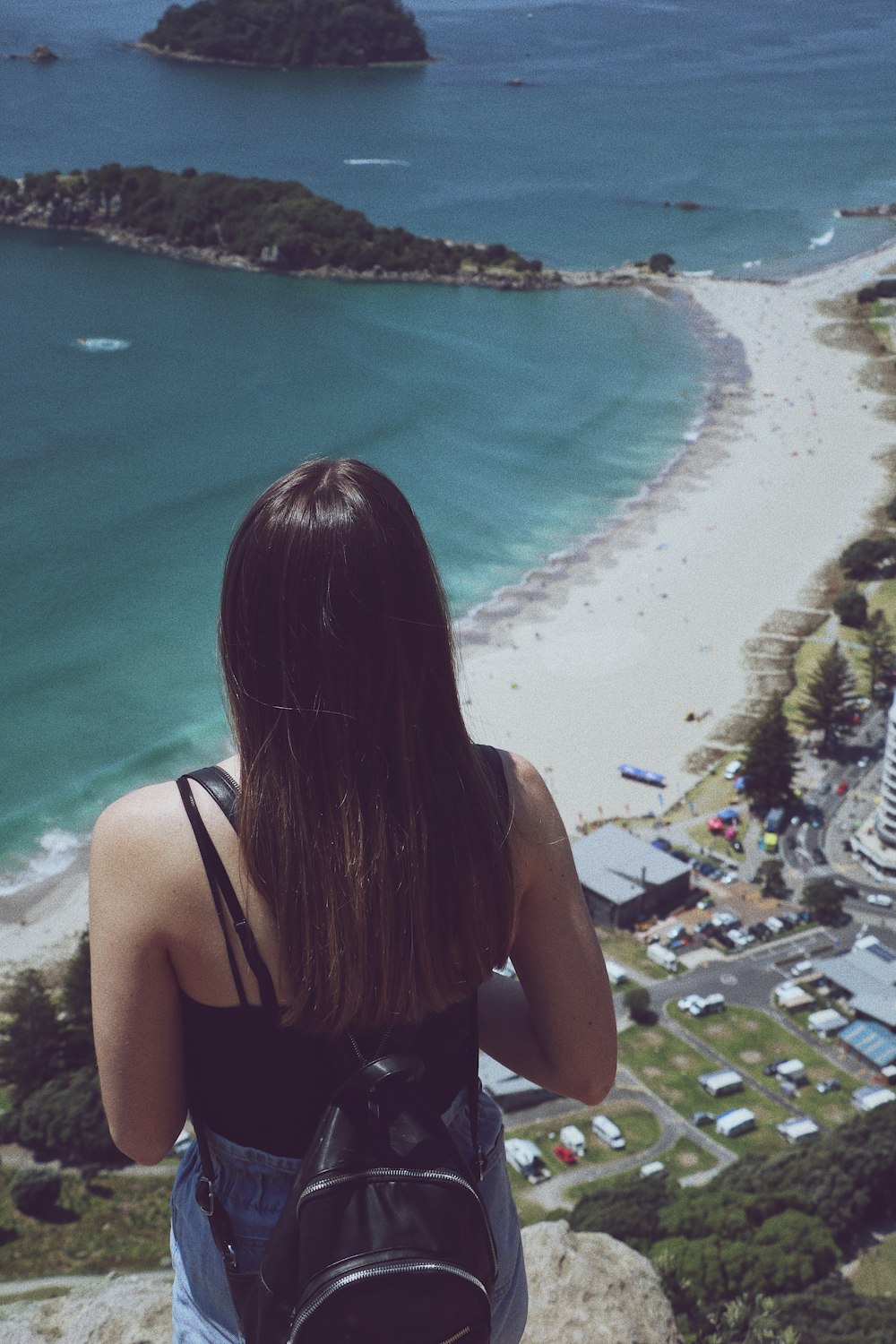 woman standing on rock overlooking shore and body of water