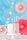 A pastel-colored cake with a marbled pink and white frosting, topped with four lit candles, is placed on a white cake stand. Decorative circular paper fans and multicolored dots adorn the background, which is primarily blue, creating a festive atmosphere.