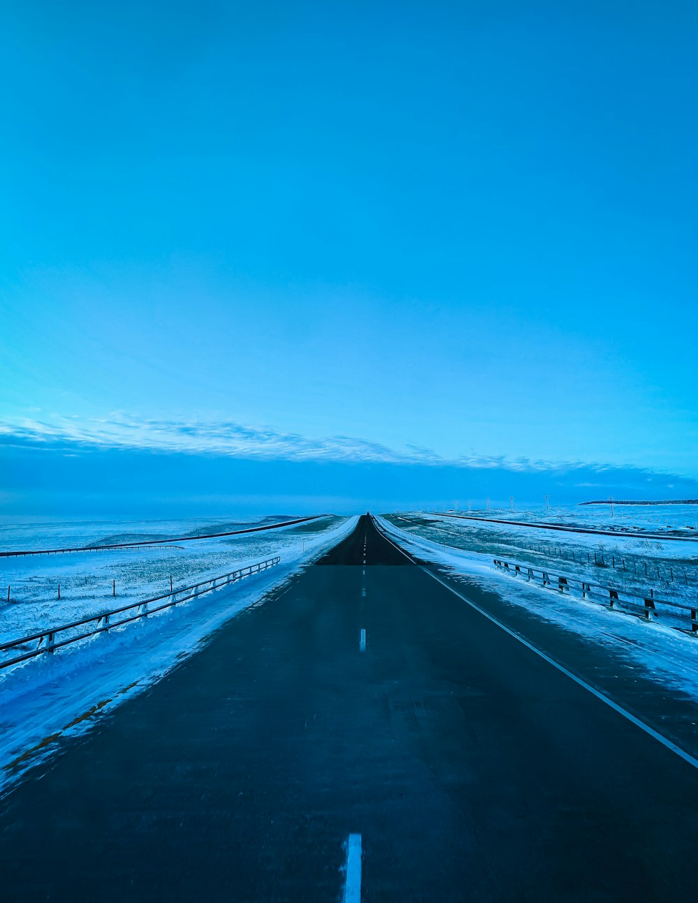 asphalt roadway beside snow field