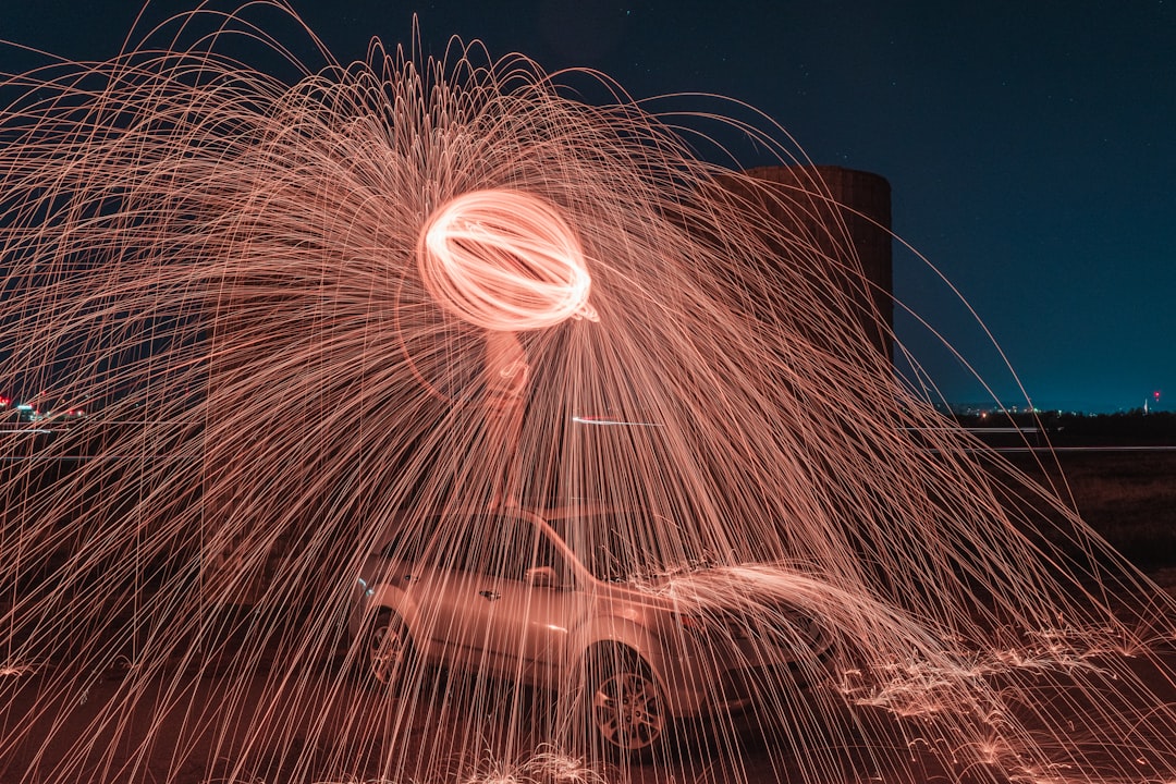 steel wool photography of person standing on vehicle at night
