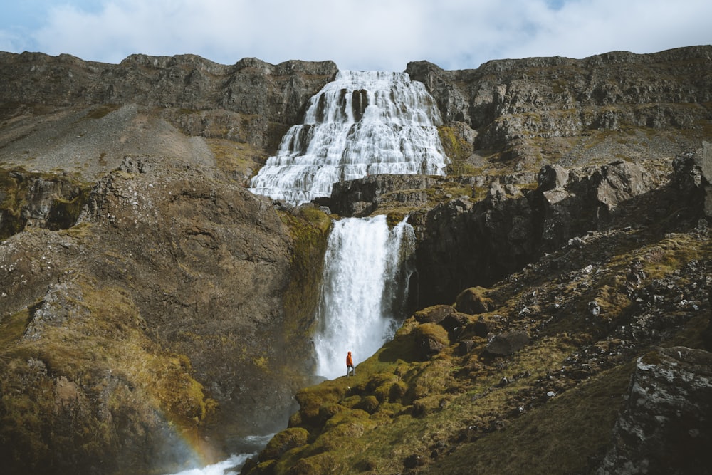 low-angle photography of waterfall under white clouds