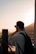 A man with a backpack taking photos of a secluded canyon landscape during golden hour.