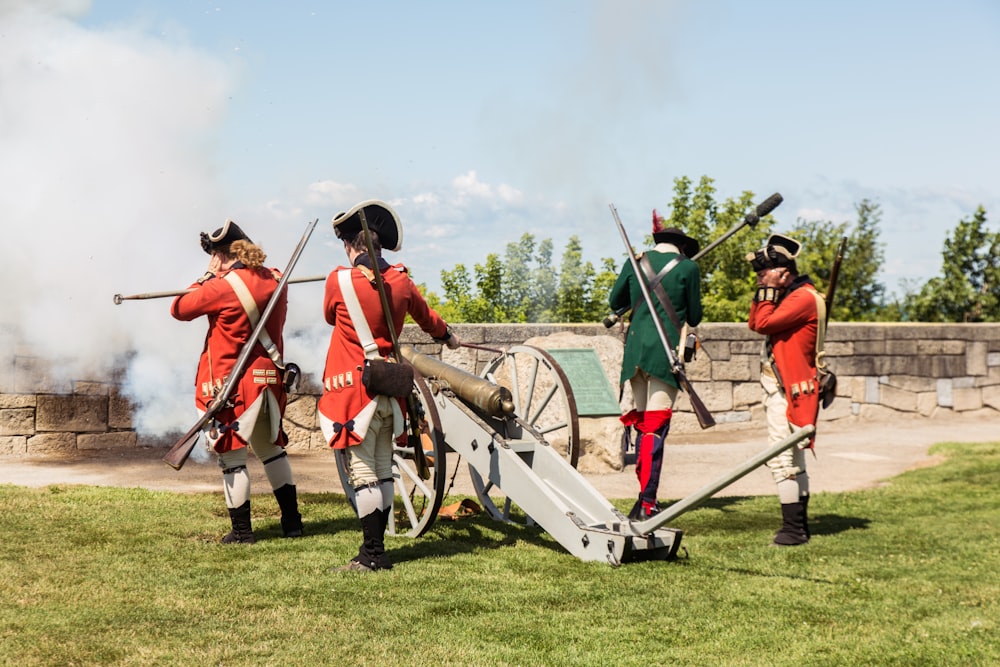 four soldiers firing canon during daytime