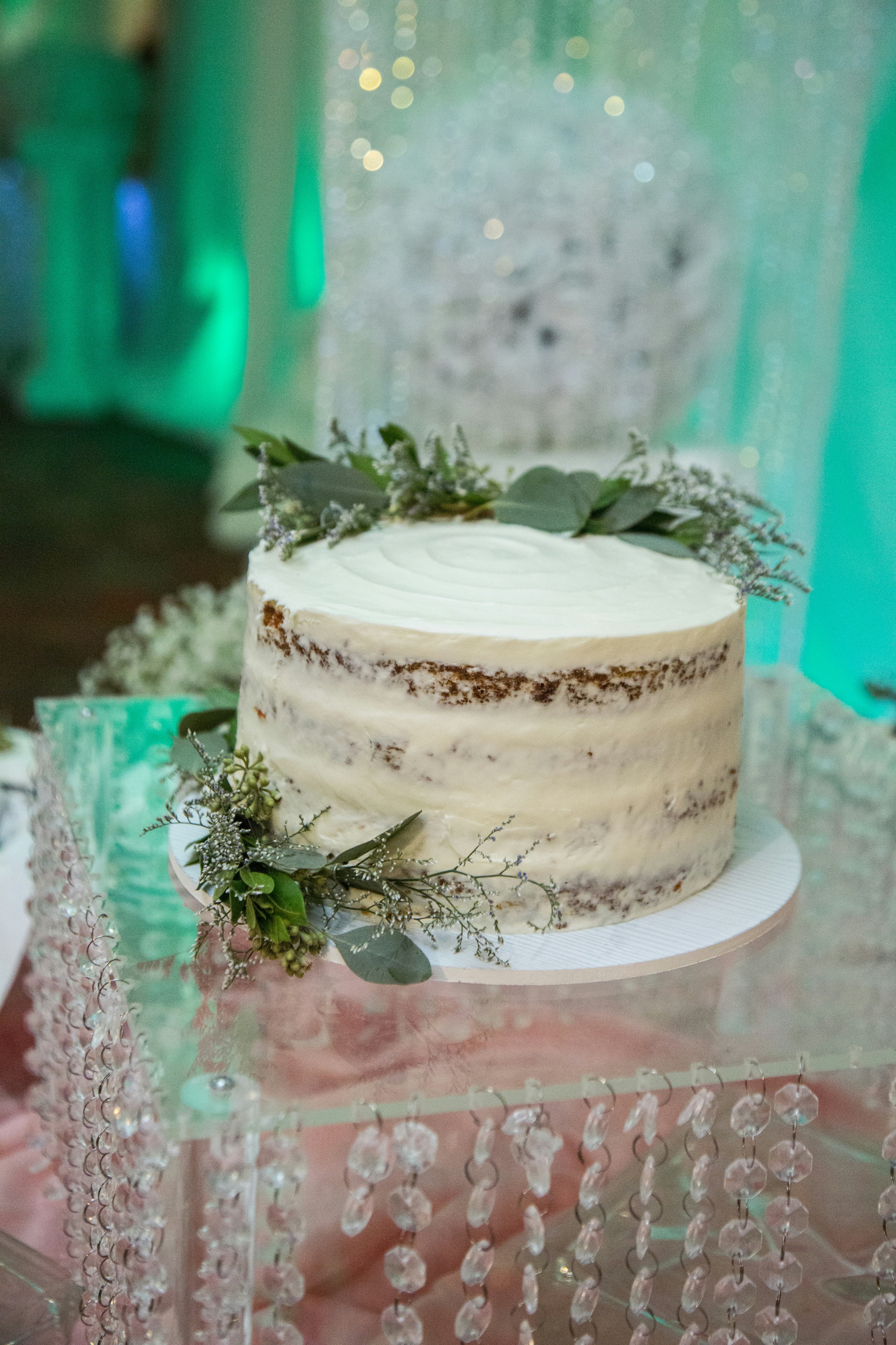 Rustic wedding cake with eucalyptus and crystal decorations and white icing.