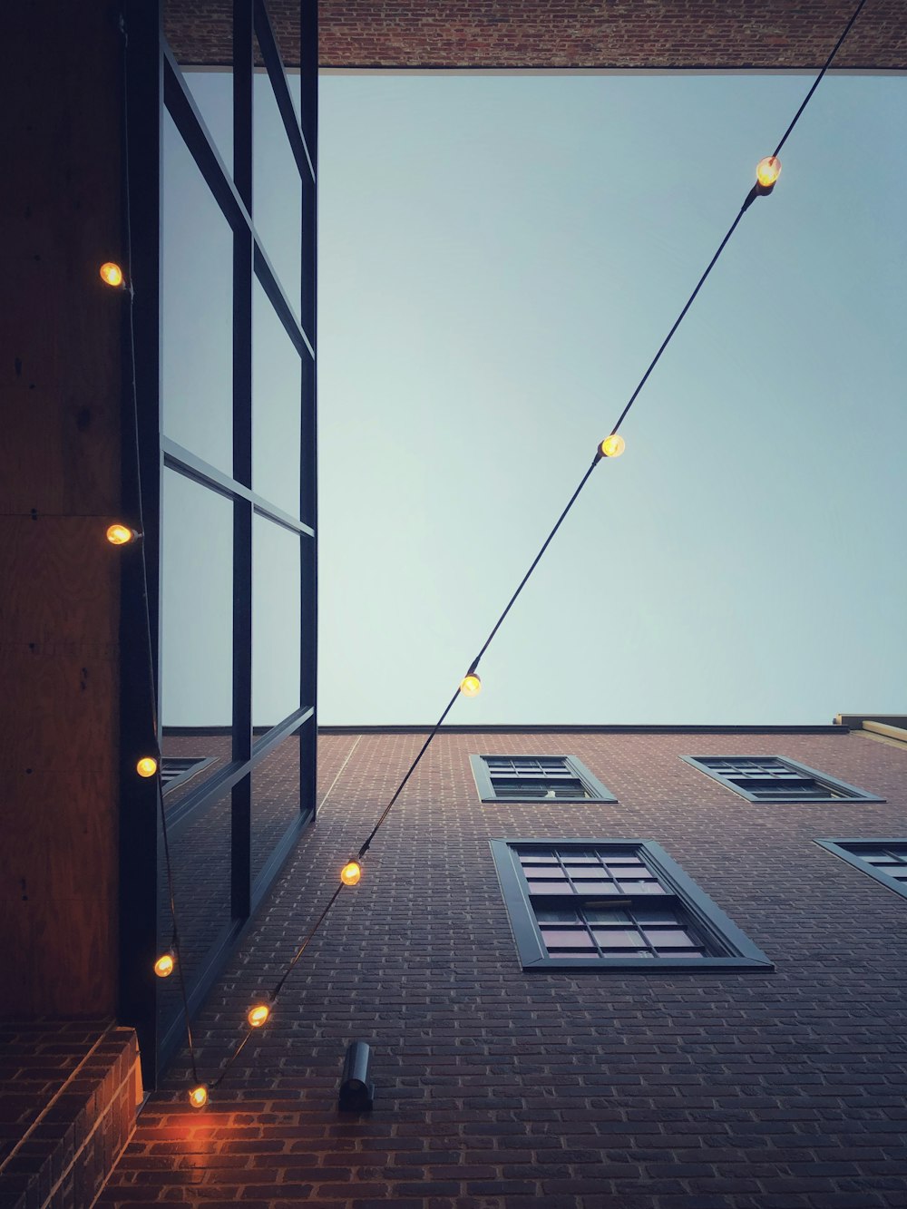 low-angle photography of turned on yellow string lights hanging on buildings