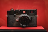 Close-up of a retro camera with bold red and black coloring against a simple backdrop.