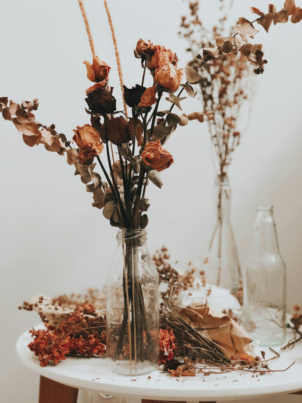 Vase aus klarem Glas mit verwelkten Rosen