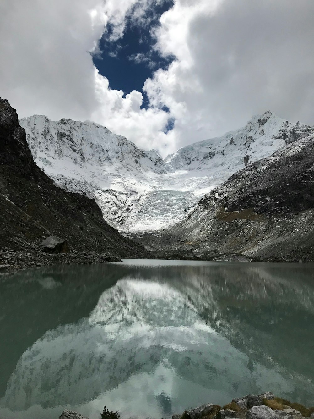 Cuerpo de agua rodeado de montañas bajo un cielo gris