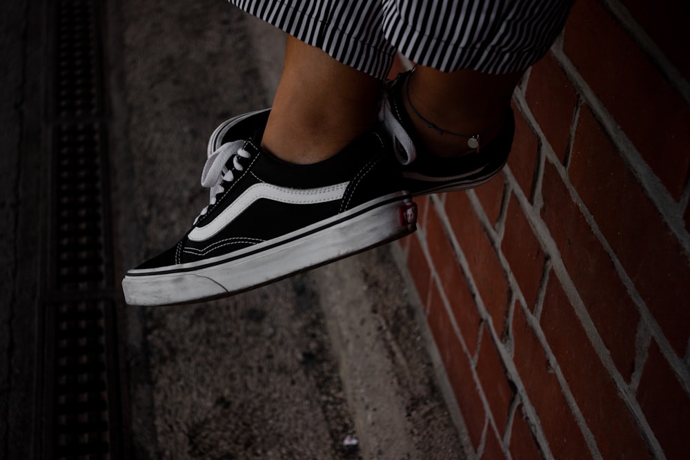 person wearing black-and-white Vans low-top sneakers