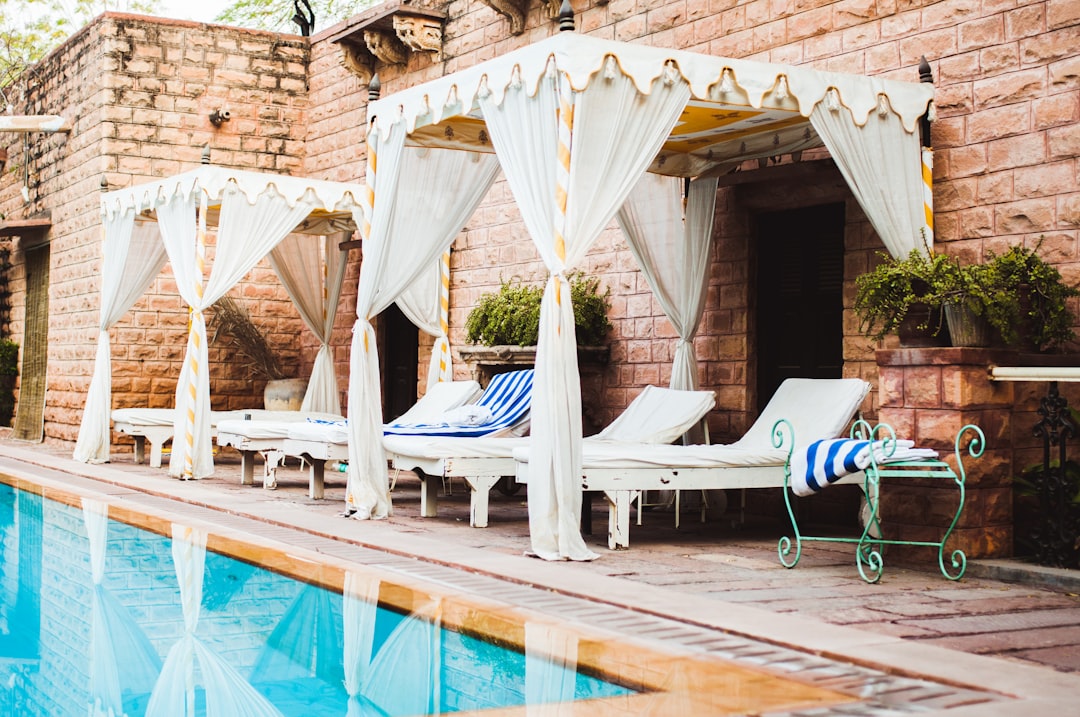 empty white loungers beside swimming pool