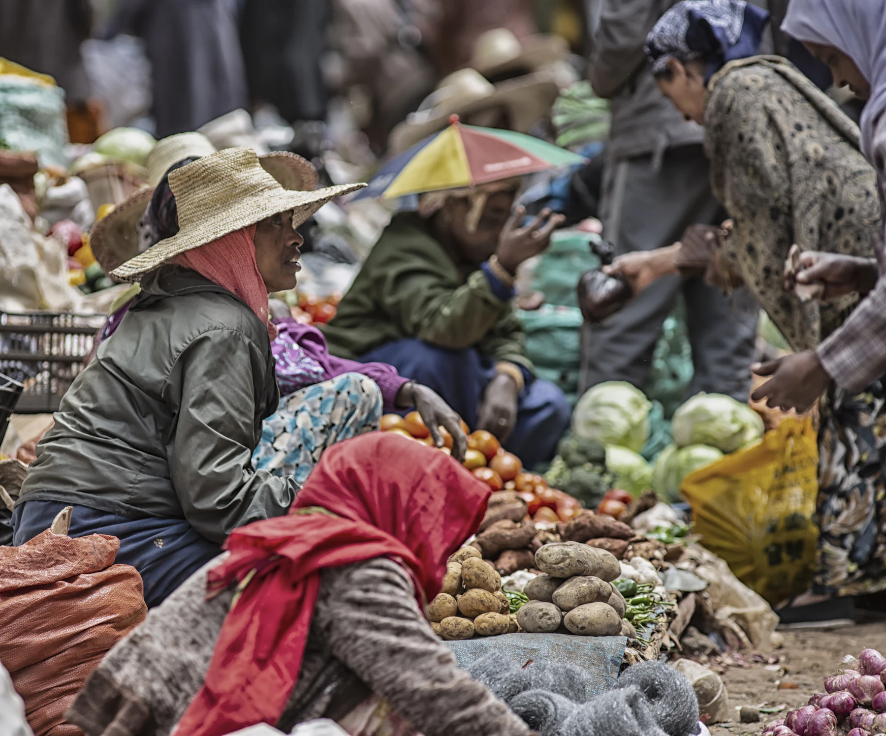 Allée de marché animée bordée d'étals de légumes