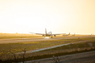 An aircraft gracefully touching down on a runway at sunset, highlighting the landing gear in action.