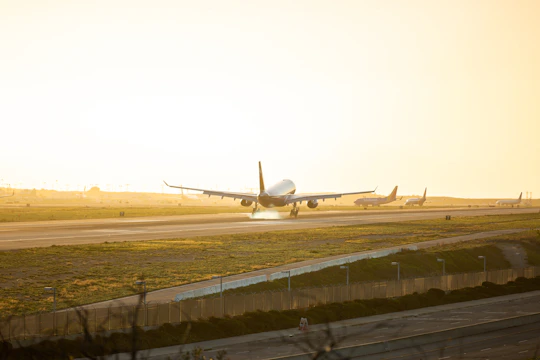 An aircraft gracefully touching down on a runway at sunset, highlighting the landing gear in action.