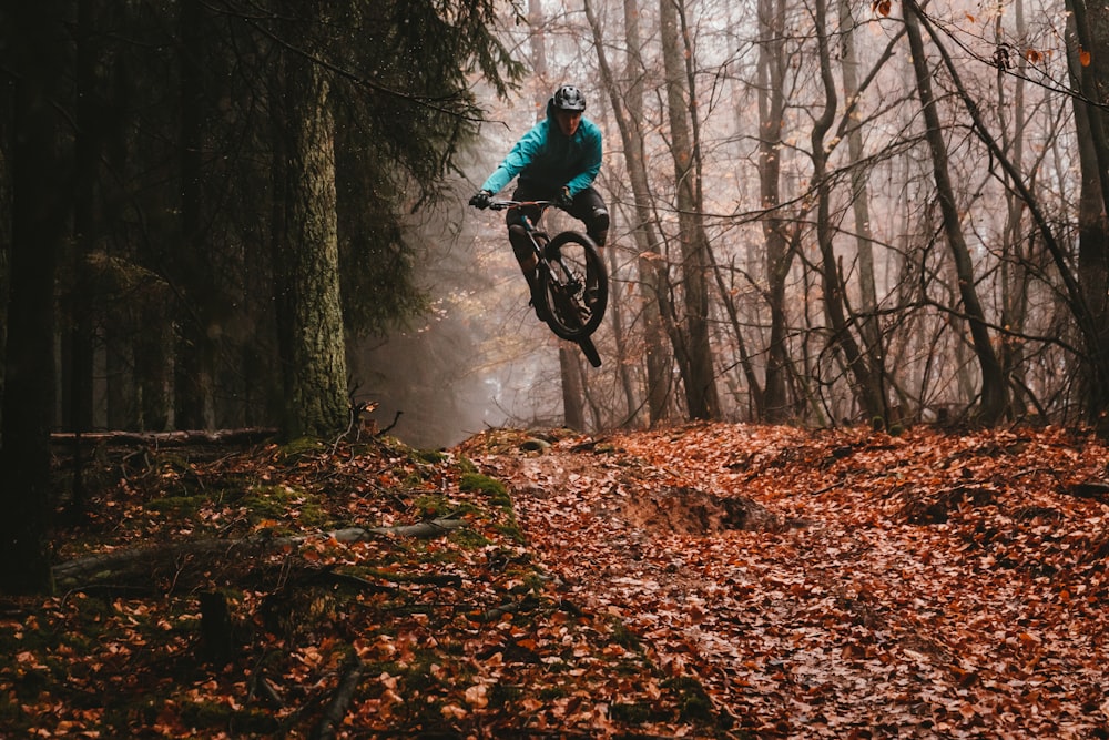 man riding bike over dried leaves on ground