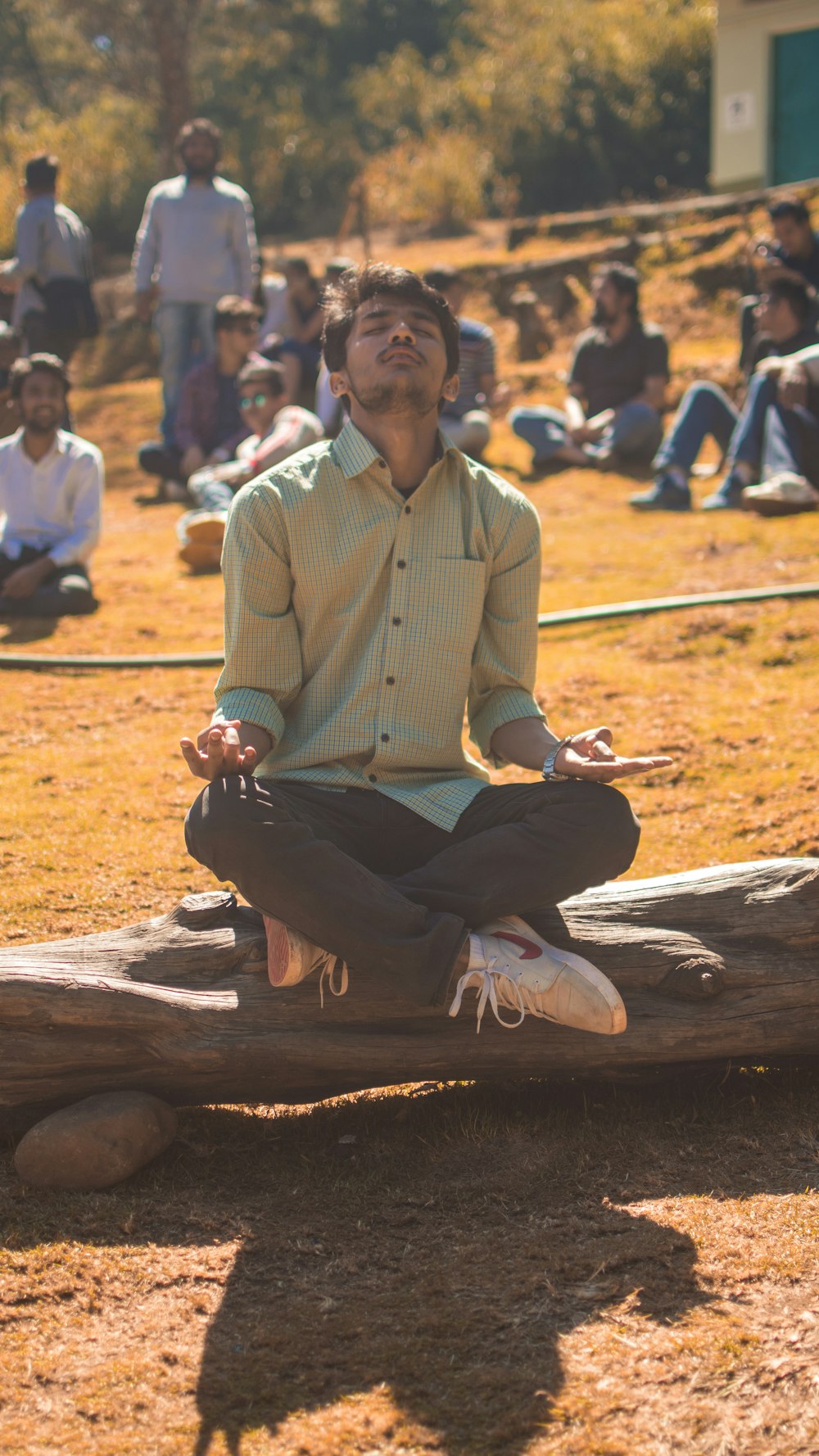 man meditating on tree log