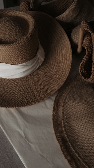 A sunlit display of elegant straw beach hats arranged on a wooden table with soft pastel backgrounds.