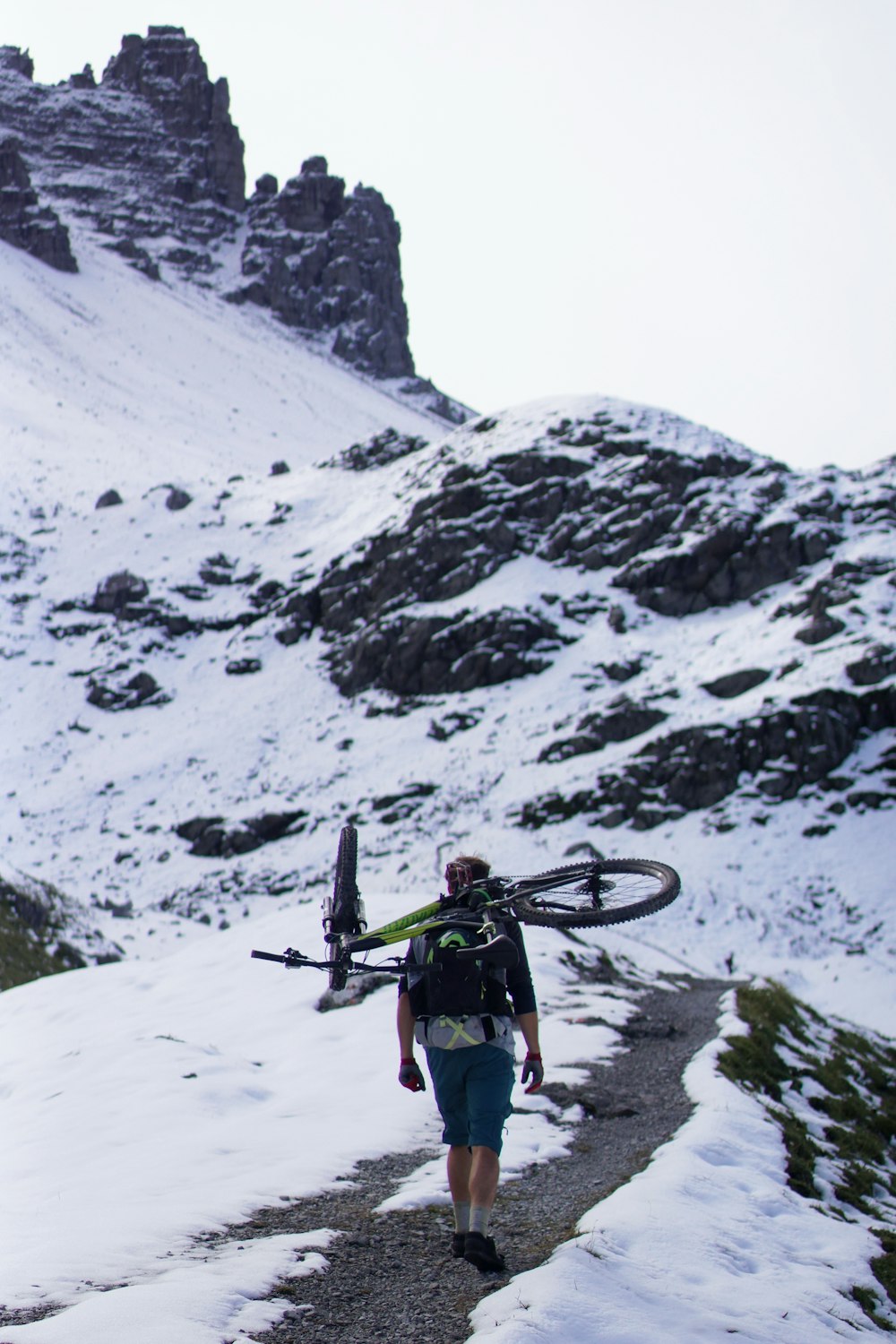 man carrying bicycle walking on mountain surrounded by snow