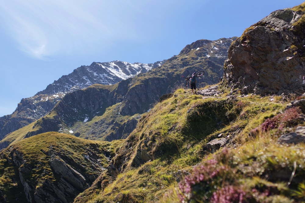 person cycling on green mountain during daytime