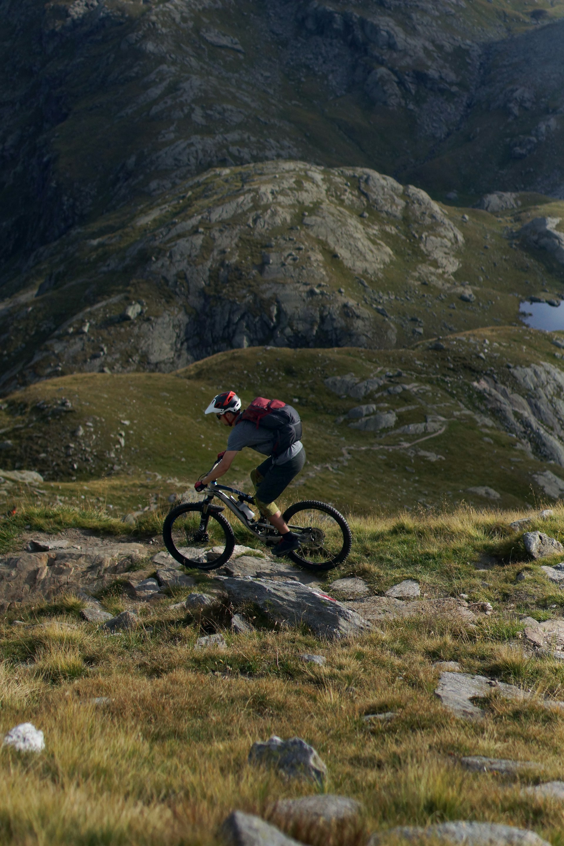 Wide-angle view of a mountain biker navigating a rugged trail, dust rising behind the wheels.