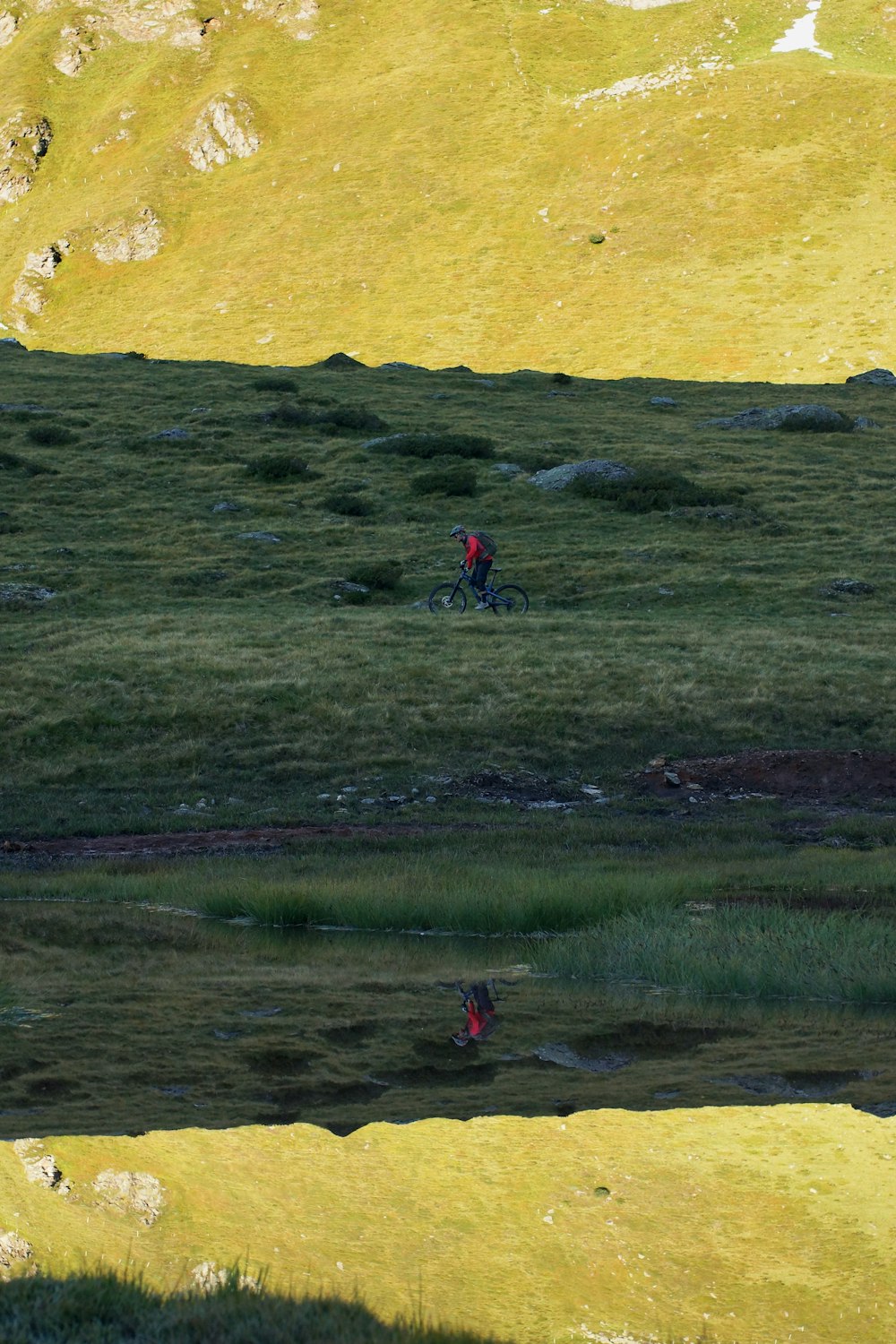 reflection photography of man riding on bicycle