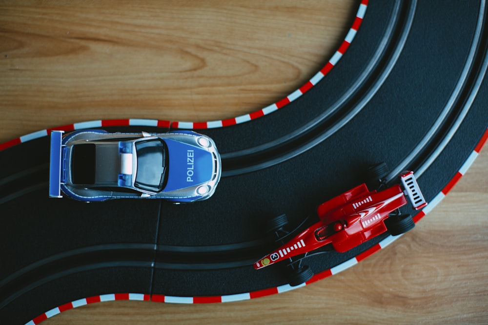 blue toy car beside red formula one toy