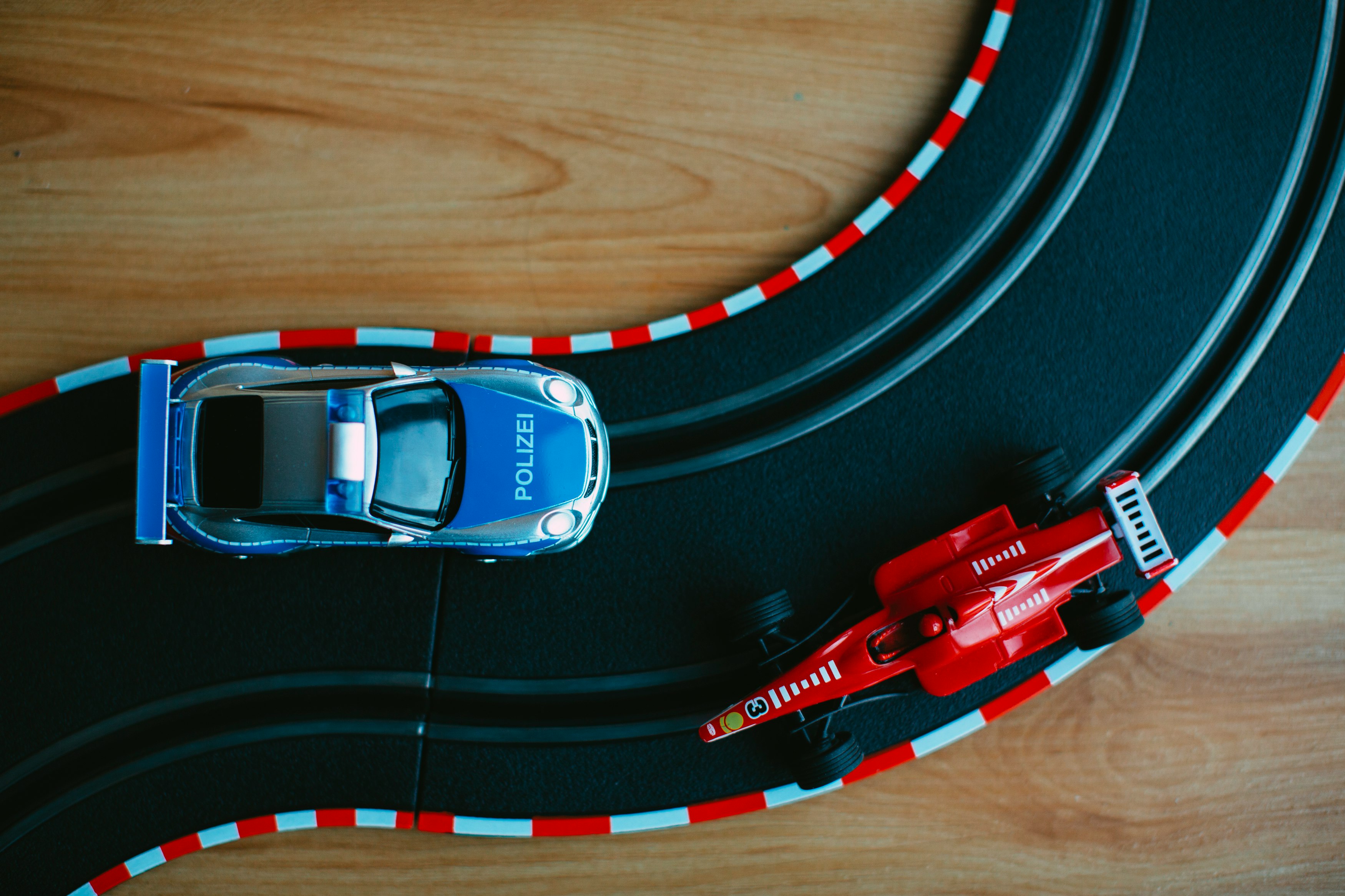 blue toy car beside red formula one toy