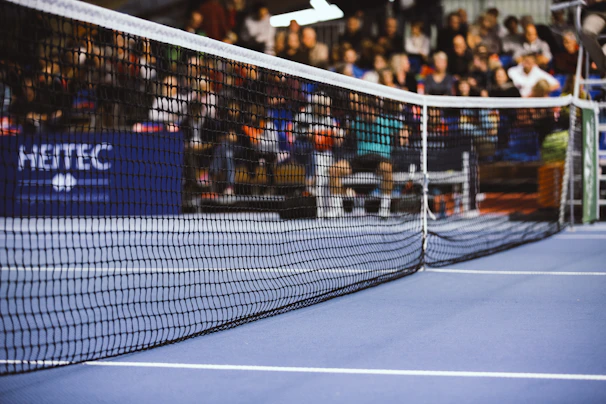A panoramic view of a tennis court with players in action and spectators watching eagerly.