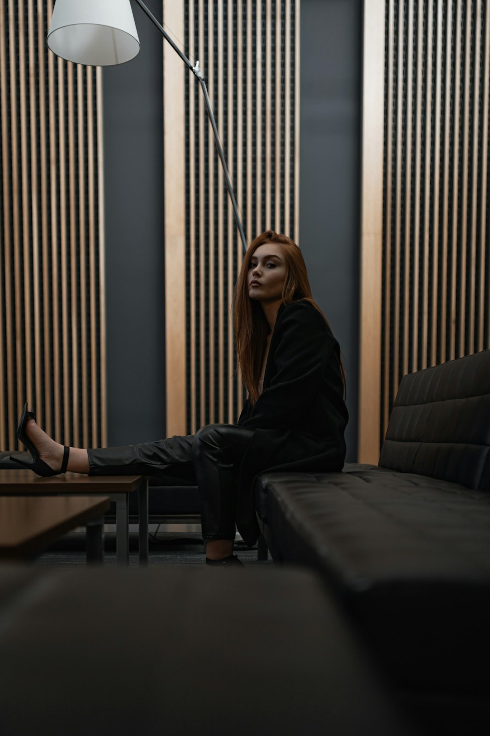 woman wearing black suit sitting on black leather sofa
