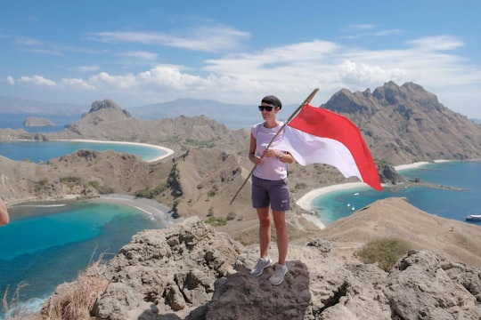 woman with a flag standing on hill during daytime in Komodo National Park Indonesia