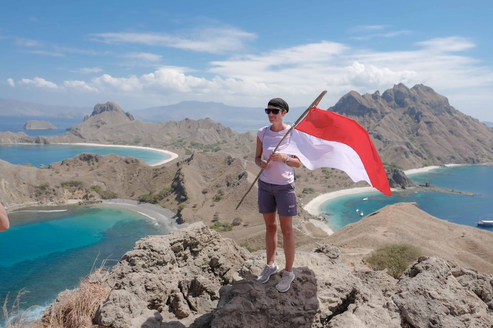 woman with a flag standing on hill during daytime