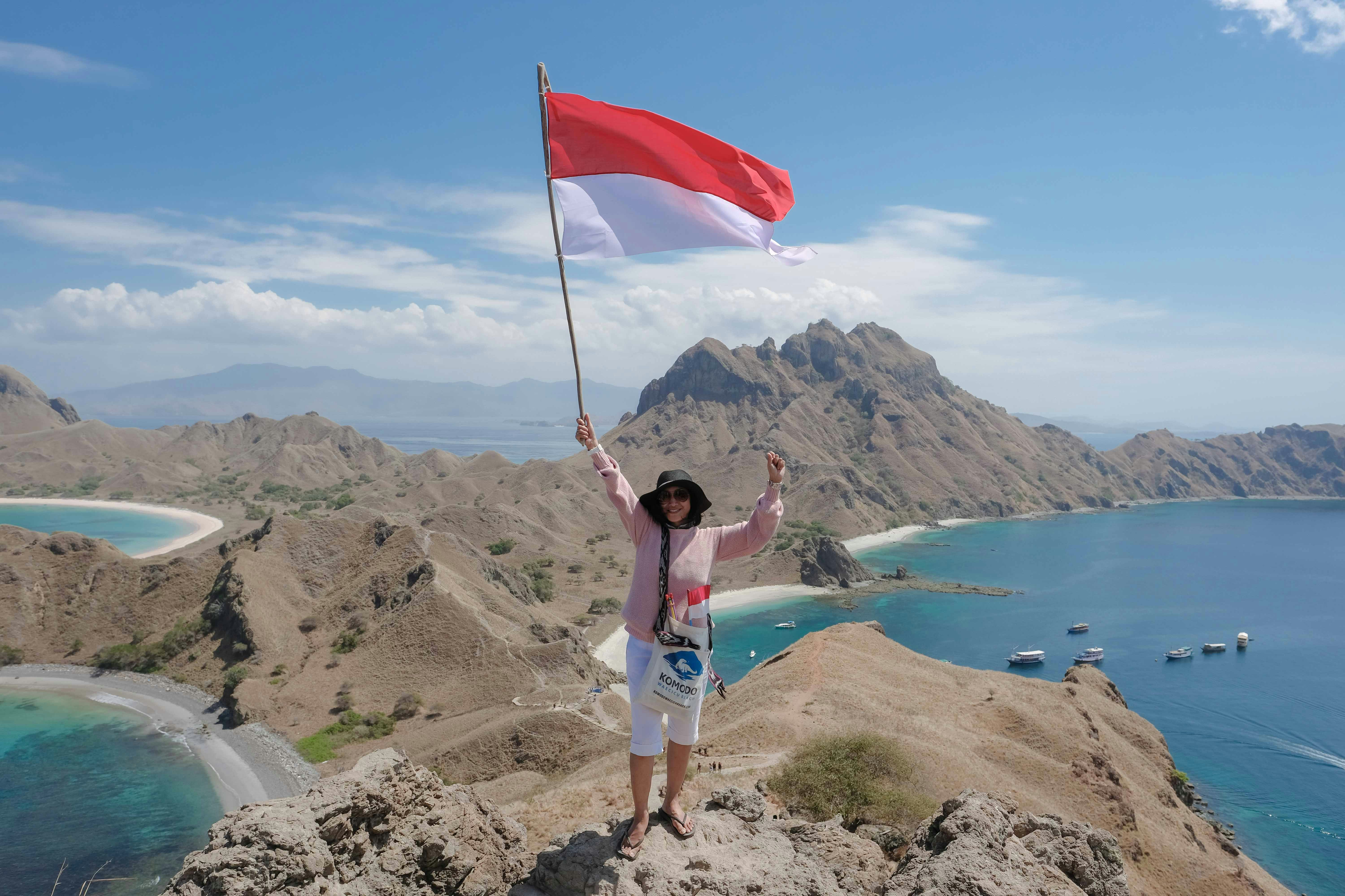 Wanita mengibarkan bendera merah dan putih di bukit