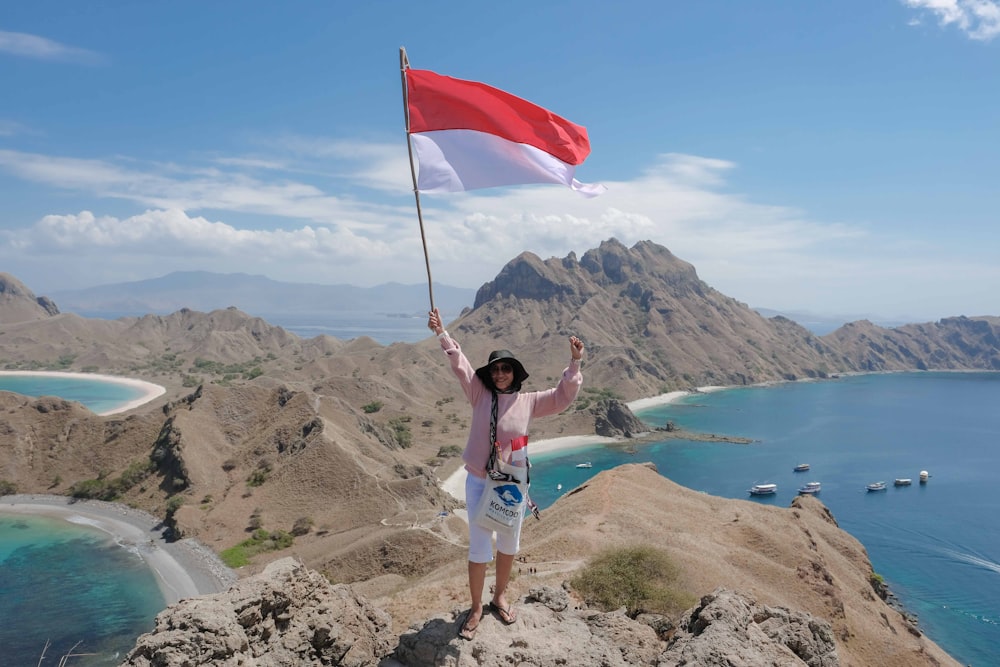 Mujer ondeando bandera roja y blanca en la colina