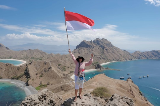 woman waving red and white flag on hill in Komodo National Park Indonesia