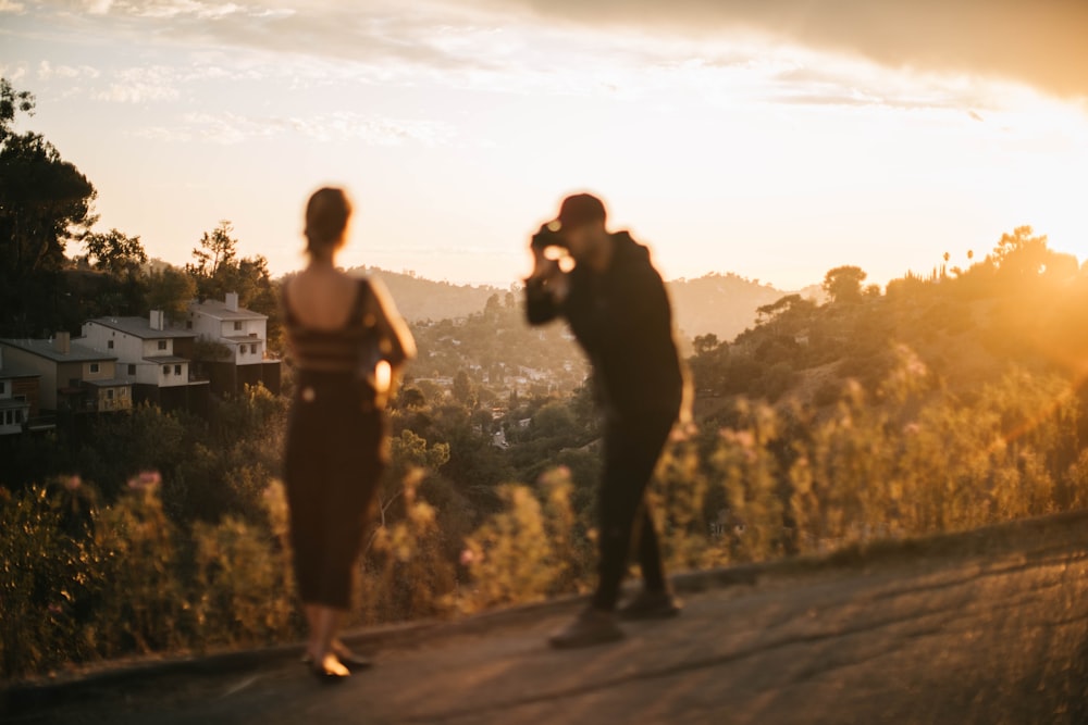 woman standing beside man holding DSLR camera