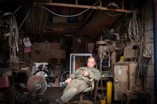 A friendly handyman answering a phone call in a cozy workshop.