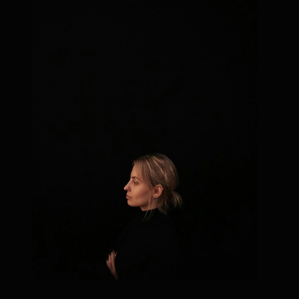 Minimalistische Fotografie einer Frau, die ein schwarzes Oberteil trägt, das zur Seite gerichtet ist