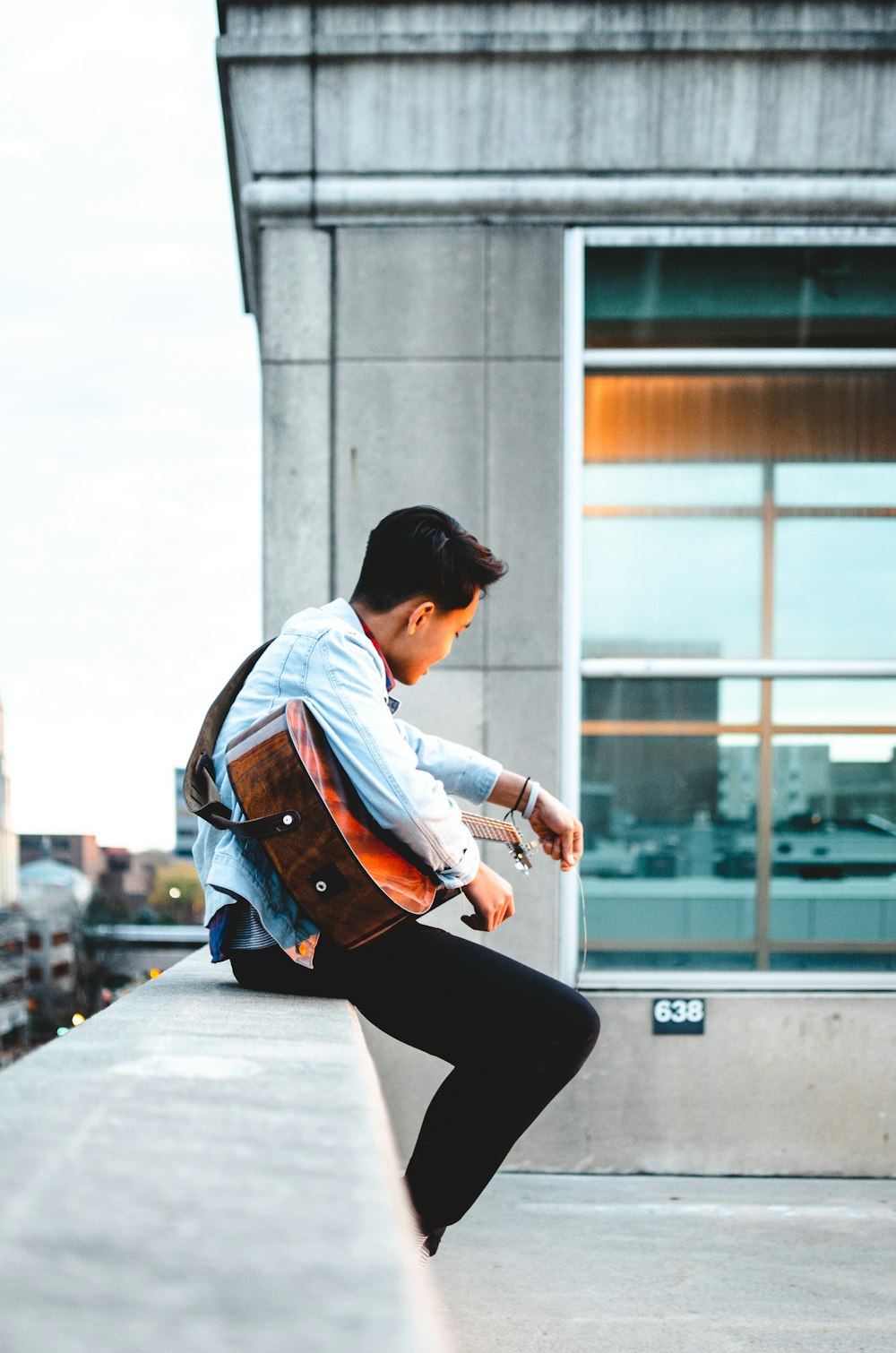 man wearing teal dress shirt and black pants playing brown acoustic guitar